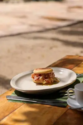 a sandwich on a plate on a wooden table at The Jungle Pearl Resort in Mto wa Mbu