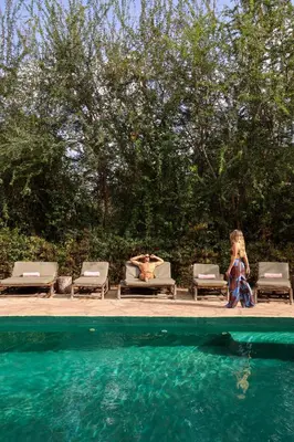 a woman is sitting next to a swimming pool at The Jungle Pearl Resort in Mto wa Mbu