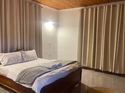 a bedroom with a bed and a shower with curtains at Toiwo Residence Arusha in Arusha