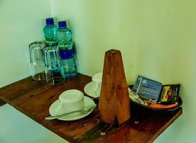 a wooden shelf with two cups and plates and water bottles at Weru Weru River Lodge in Moshi