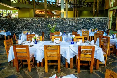 a dining room with white tables and wooden chairs at Weru Weru River Lodge in Moshi