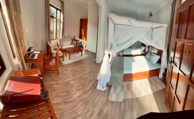 a bedroom with a canopy bed and a living room at Wademac Arusha Inn Hotel in Arusha