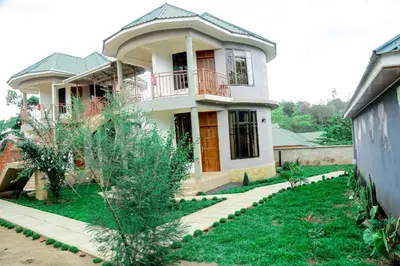 a house with a balcony and a yard at Wademac Arusha Inn Hotel in Arusha