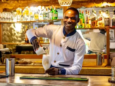 a chef standing behind a counter in a kitchen at Mount Meru Game Lodge in Arusha