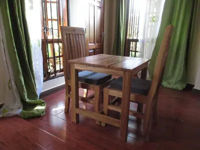 a wooden table and chairs in a room with a window at Darema Homestay in Arusha
