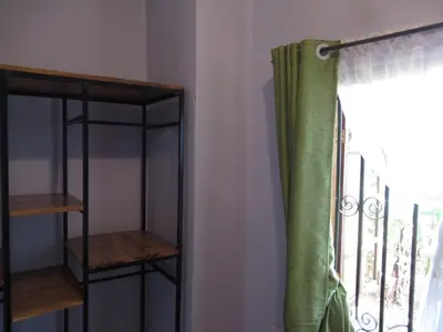 a room with a window with a curtain and a shelf at Darema Homestay in Arusha