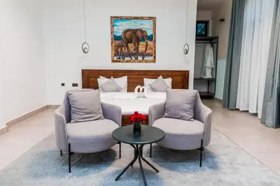 a bedroom with a bed and two chairs and a table at Shose Farmhouse Chalets & Campsite in Moshi