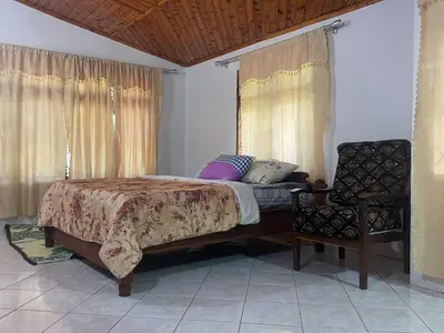 a bedroom with a large bed and a chair at Joe & El Heritage Villa in Mwika