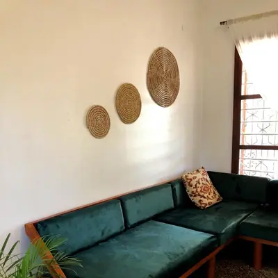 a living room with a green couch and three baskets on the wall at Goodtimewithfar House in Moshi