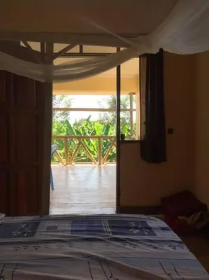 a bedroom with a bed with a view of a porch at The Hondo Hondo House, Mto wa Mbu, Tanzania in Mto wa Mbu