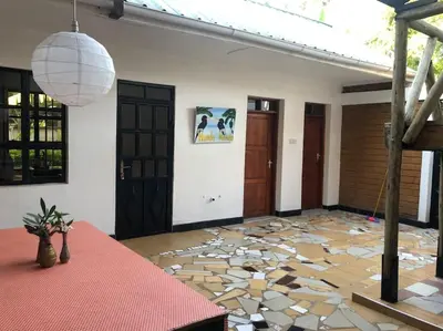 a room with a stone floor and doors and a table at The Hondo Hondo House, Mto wa Mbu, Tanzania in Mto wa Mbu
