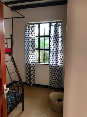 a room with a window with curtains and a ladder at The Hondo Hondo House, Mto wa Mbu, Tanzania in Mto wa Mbu