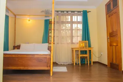 a bedroom with a bed and a table and a window at Otakef Motel in Arusha