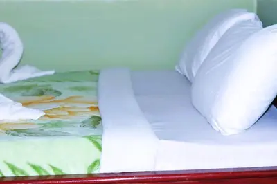 a bed with white sheets and pillows on it at Otakef Motel in Arusha